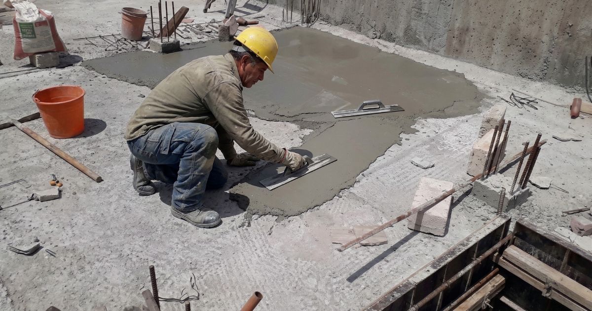 Albañil poniendo mezcla para nivelsr losa