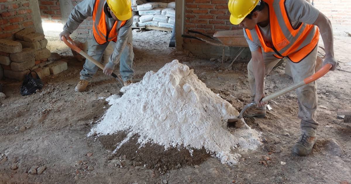 Albañiles preparando mezcla con cal y arena para pegar block